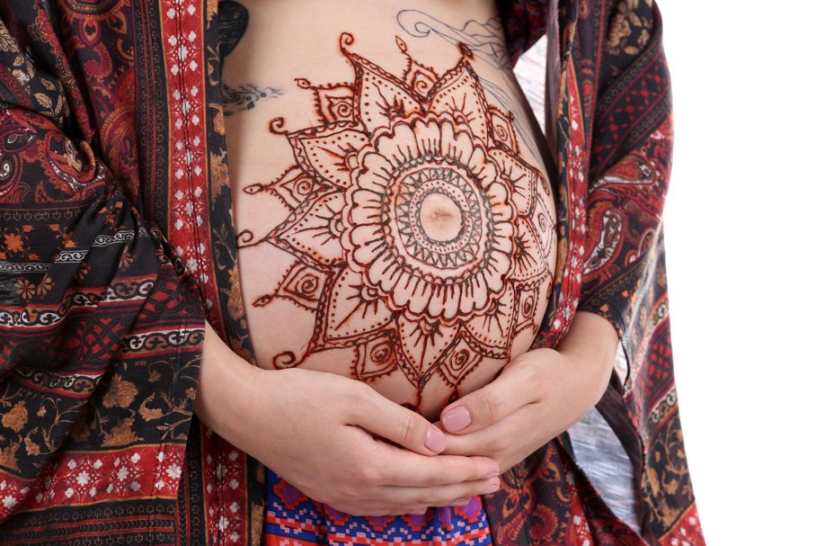 Kobieta w ciąży z tatuażem z henny na brzuchu.